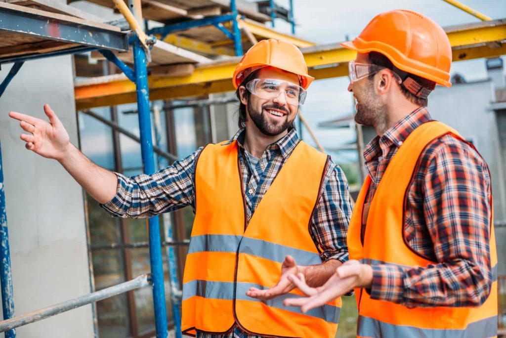 Architectural Steel Detailing: Combine Function & Design | Tekla 3D Modeling 4 happy builders in reflective vest and hard hat pointing at building house